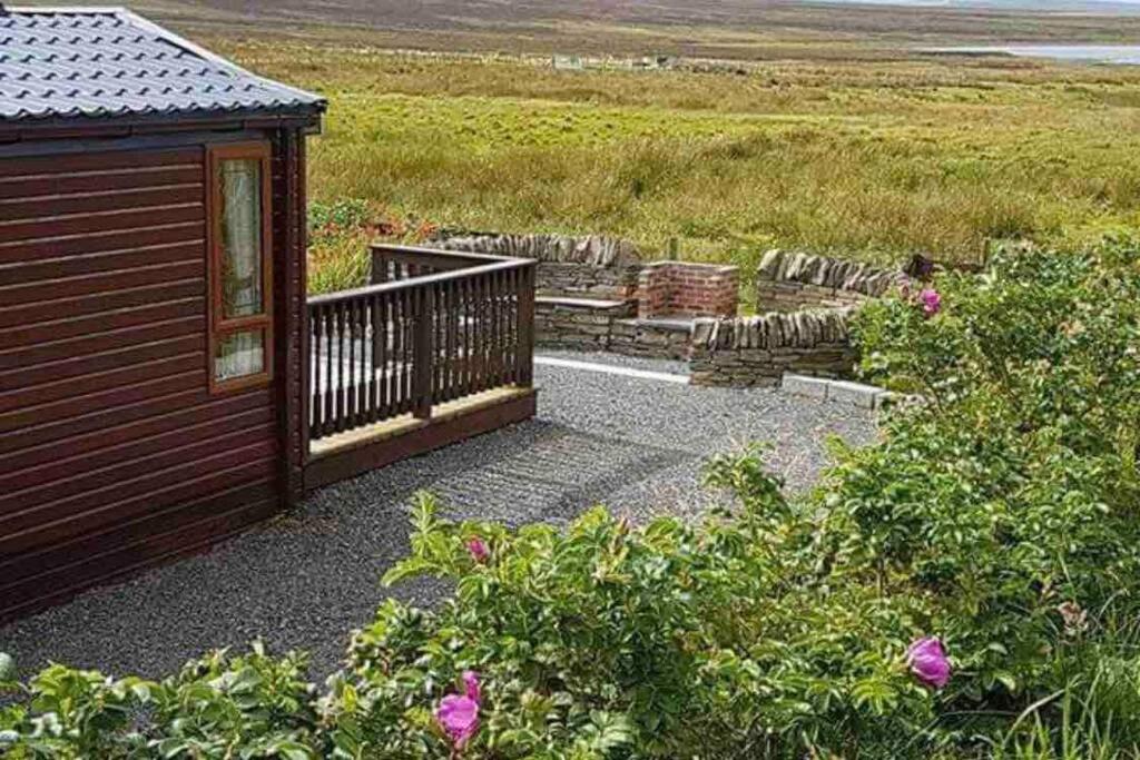 a wooden cabin with a balcony and some flowers at Rymmon Retreat in Orkney