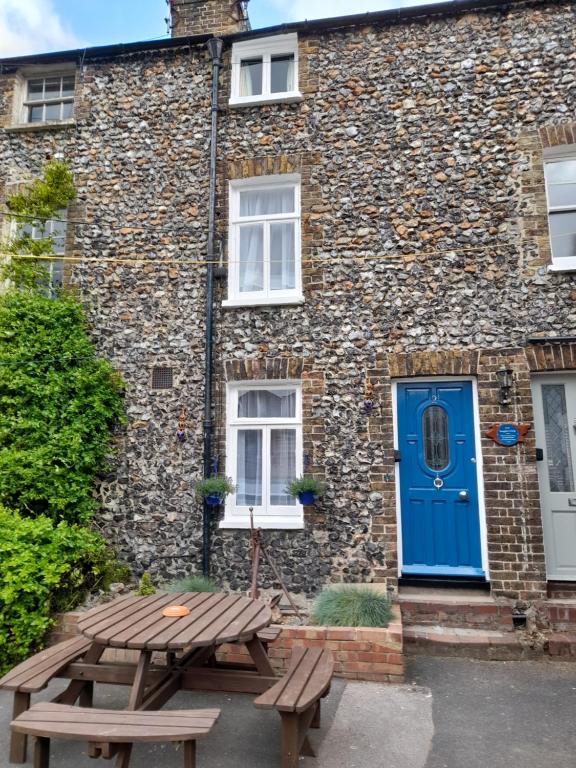 a building with a blue door and a picnic table at Smuggler's Cottage Broadstairs in Broadstairs