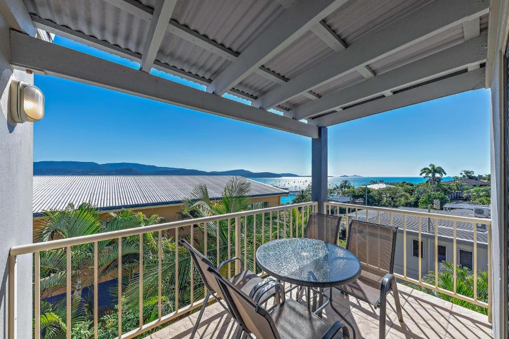 a patio with a table and chairs on a balcony at Airlie Sunset Waterview Apartment in Airlie Beach