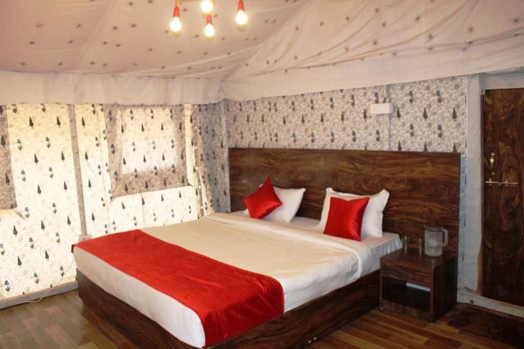 1 dormitorio con 1 cama grande con almohadas rojas en Adventure Camping, en Pachmarhī