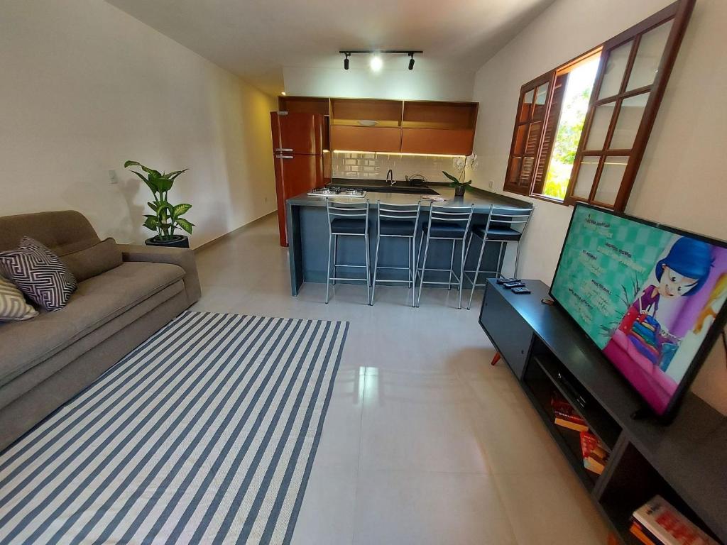 Una sala de estar con un sofá y una cocina. en Catimbau - Flat com Piscina, 50mt da praia, churrasqueira privativa, ar con, wi-fi, netflix, en Paraty