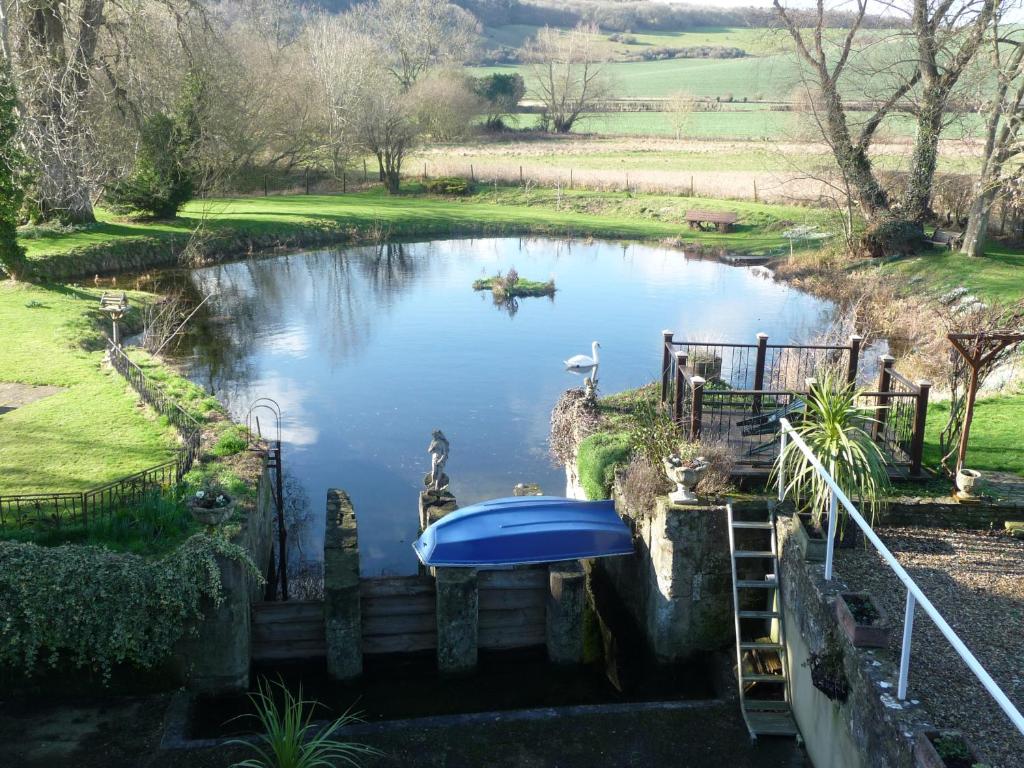 a pond with two swans and a boat in it at Salisbury Old Mill House in Salisbury