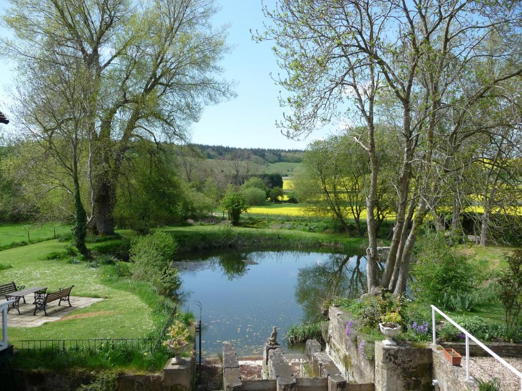 a pond in a park with a bench and trees at Salisbury Old Mill House in Salisbury