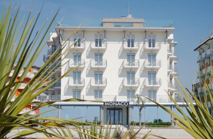 un gran edificio blanco con un cartel delante en Hotel Monaco en Caorle