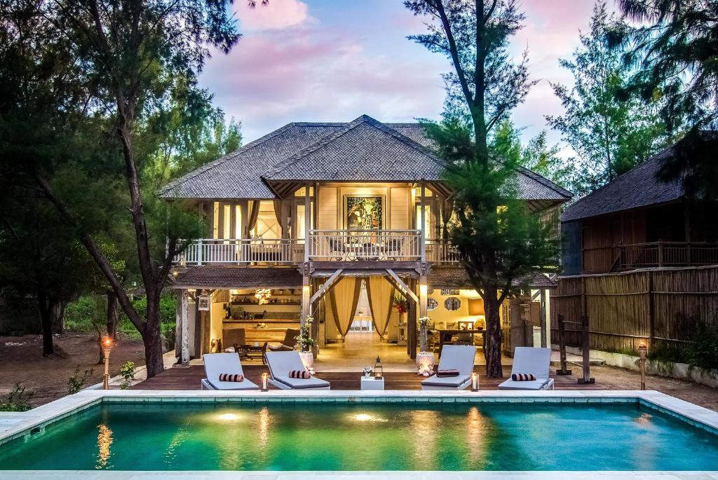 eine Villa mit einem Pool und einem Haus in der Unterkunft Coral Flora Villa Beach Front in Gili Trawangan