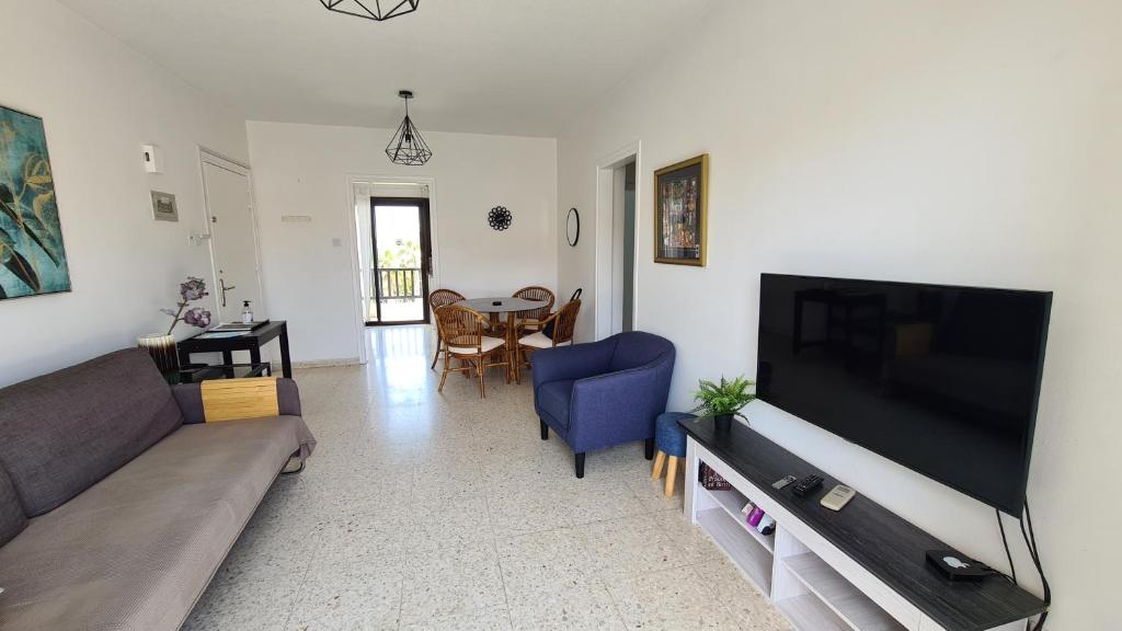 a living room with a couch and a flat screen tv at Kings Avenue - Natalia's Apt in Paphos