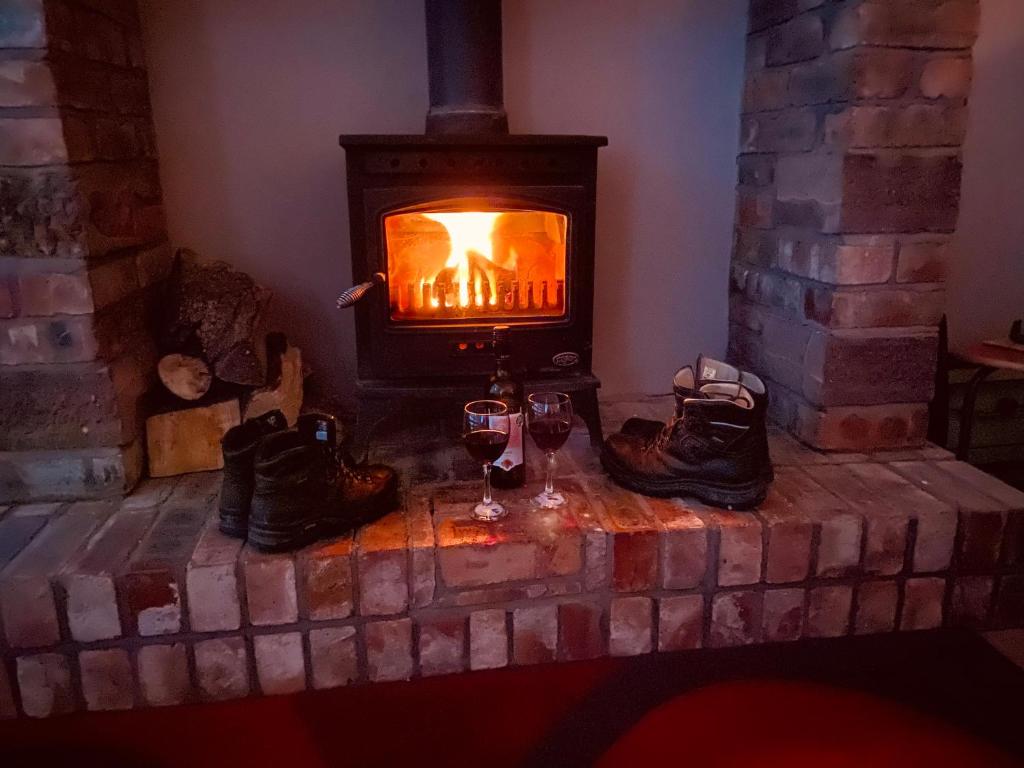 a fireplace with two glasses of wine and shoes at Parkside Mews in Frizington