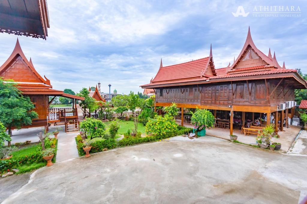 un grand bâtiment en bois avec un toit rouge dans l'établissement Athithara Homestay, à Phra Nakhon Si Ayutthaya