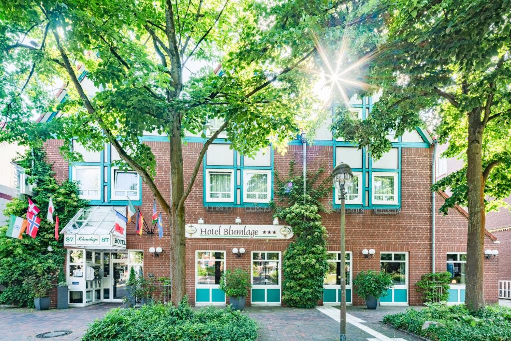 een gebouw van rode baksteen met blauwe ramen en bomen bij Hotel Blumlage in Celle