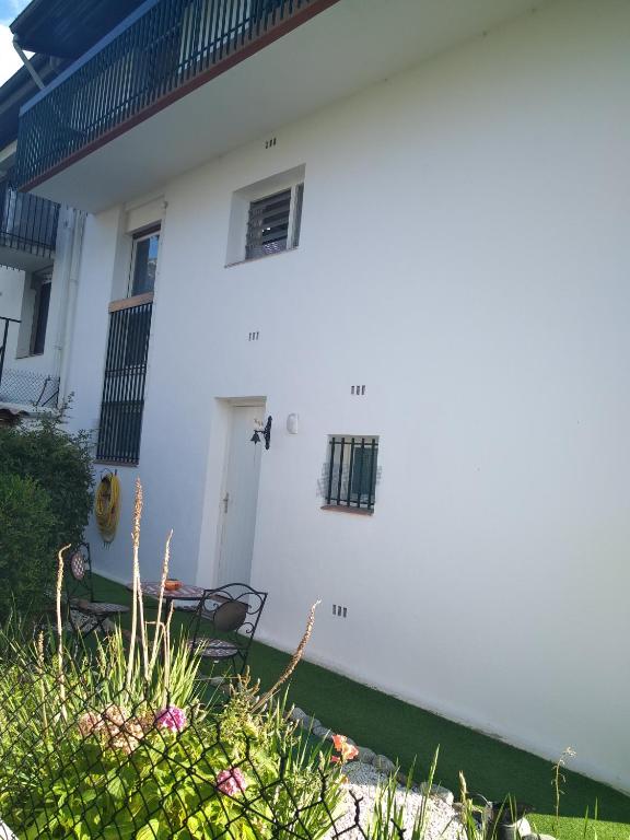 une maison blanche avec un banc devant dans l'établissement Appart Rez de Jardin Chez Anne, à Vernet-les-Bains