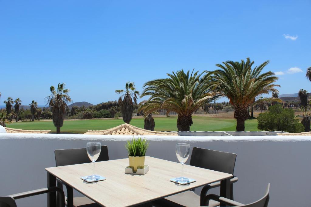 a table with two wine glasses and palm trees at Vista Bonita, Golf del Sur in San Miguel de Abona