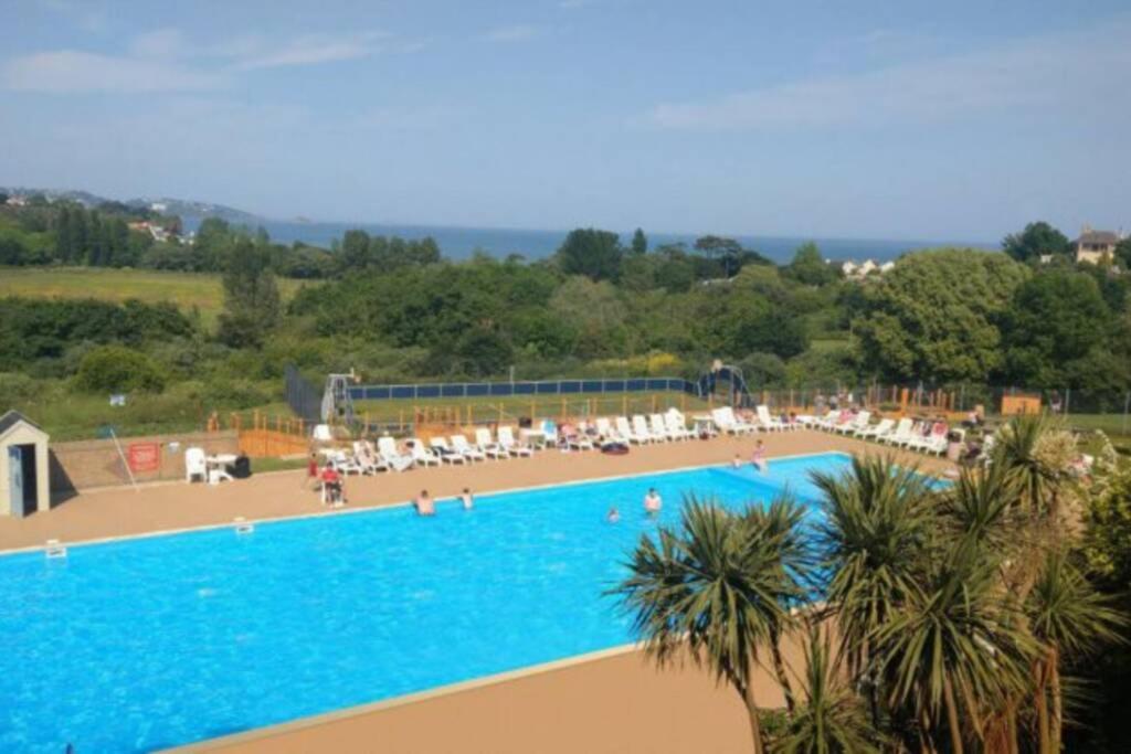 a large swimming pool with people sitting around it at Hoburne Devon Bay Static 3 Bed in Goodrington