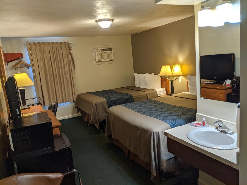 Patriot Stay Motel في فيرنال: غرفة فندقية بسريرين ومغسلة