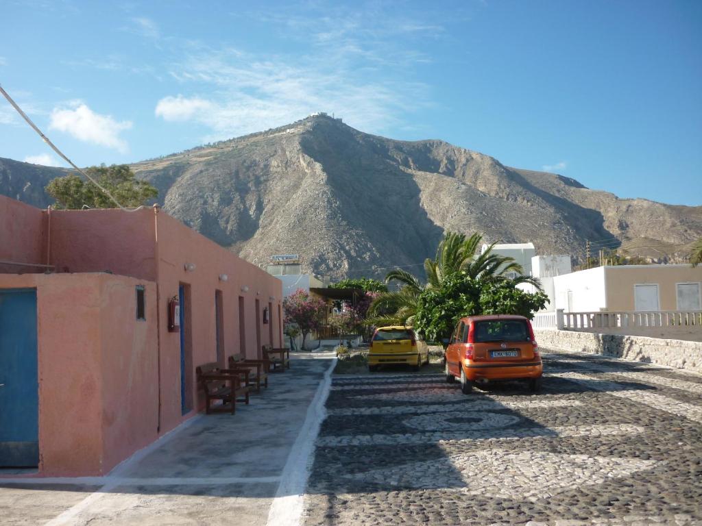 a mountain in the distance with cars parked on a street at Agios Antonios in Perissa