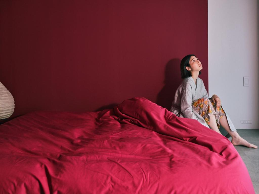 a woman sitting on a bed under a red blanket at MN Building - Vacation STAY 11194 in Nagoya