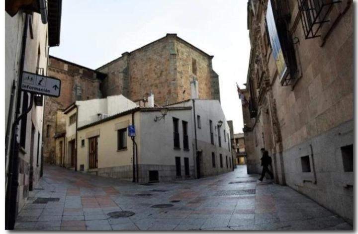 a person walking down an alley with an old building at La casa de Tentenecio in Salamanca