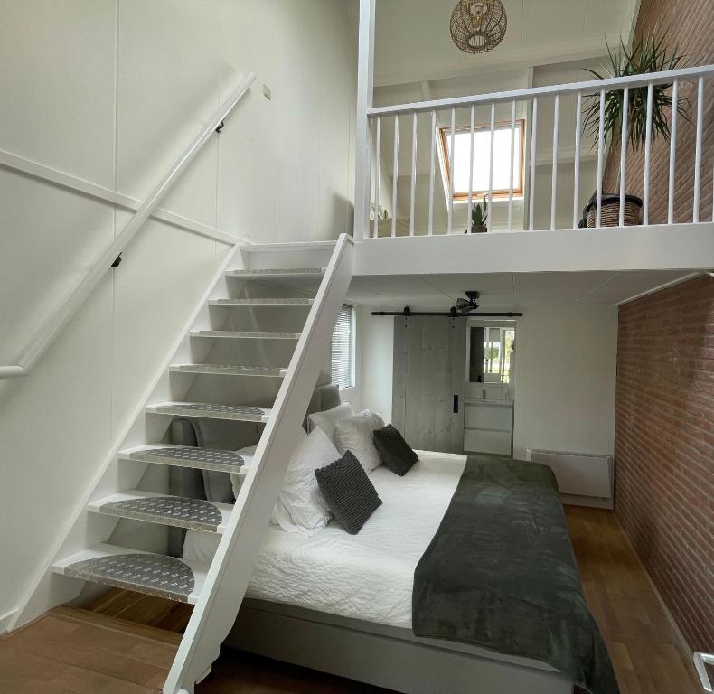 a bedroom with a bed under a staircase at Logeren bij Grea in Zwartsluis