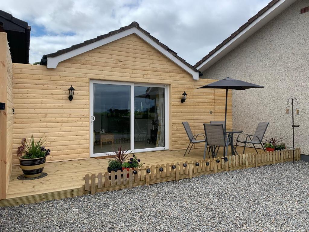 a wooden deck with a table and chairs and an umbrella at TomaX Garden Cabin Free Parking in Inverness