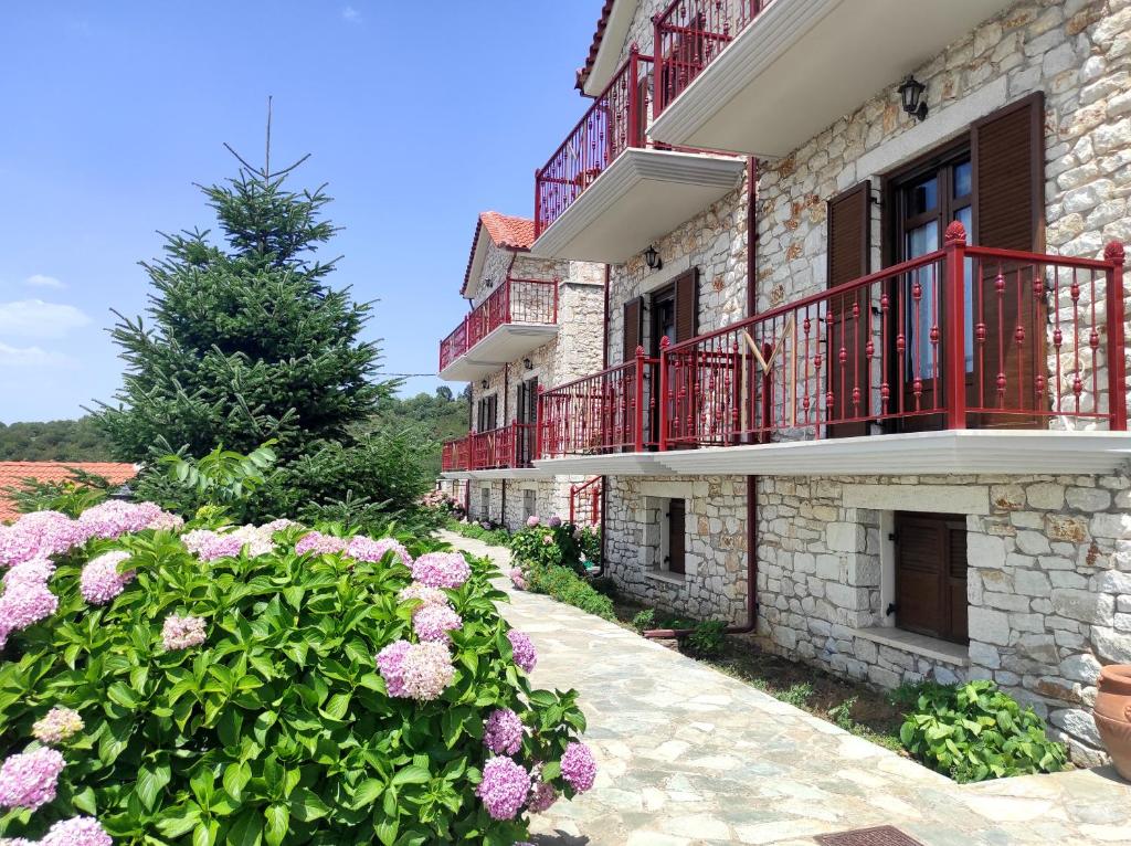 um edifício com varandas vermelhas e flores cor-de-rosa em Meterizi Guesthouse em Varvítsa