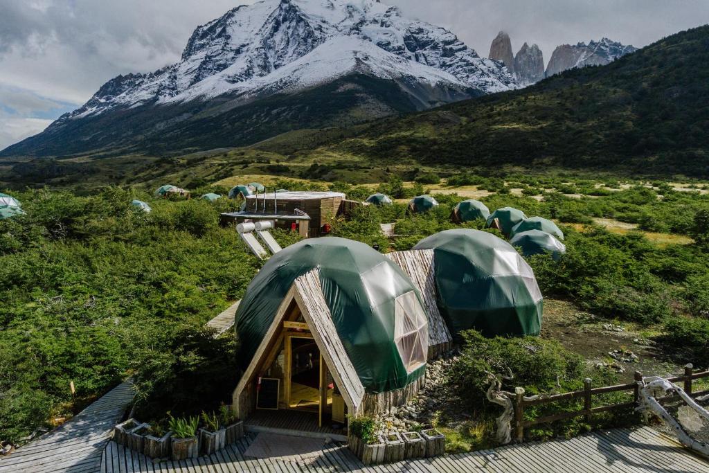 grupa zielonych namiotów przed górą w obiekcie Ecocamp Patagonia w mieście Torres del Paine