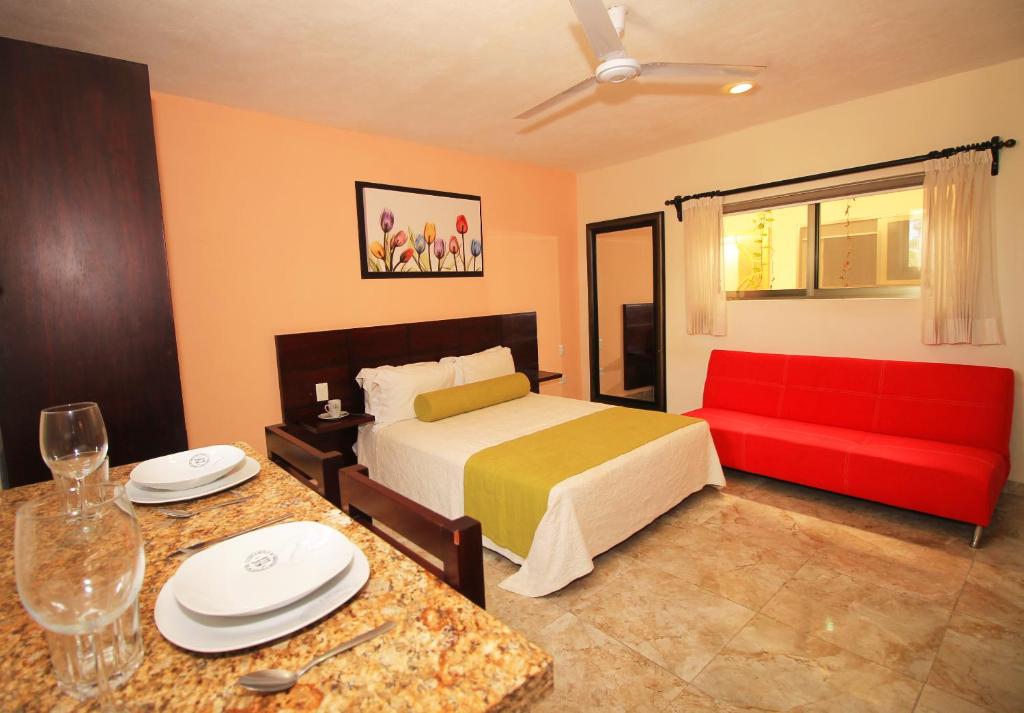 a hotel room with a bed and a red couch at Papagayo Hotel Boutique in Playa del Carmen