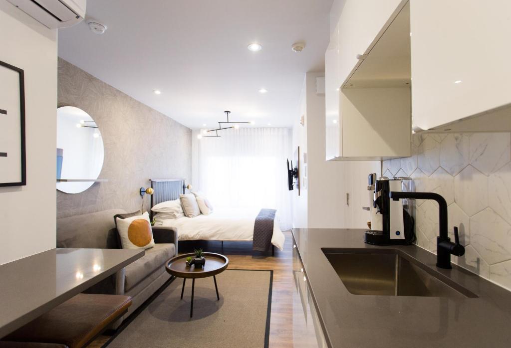eine Küche und ein Wohnzimmer mit einem Bett im Hintergrund in der Unterkunft The Santamaria Golden Palms Studio by Den Stays in Montreal