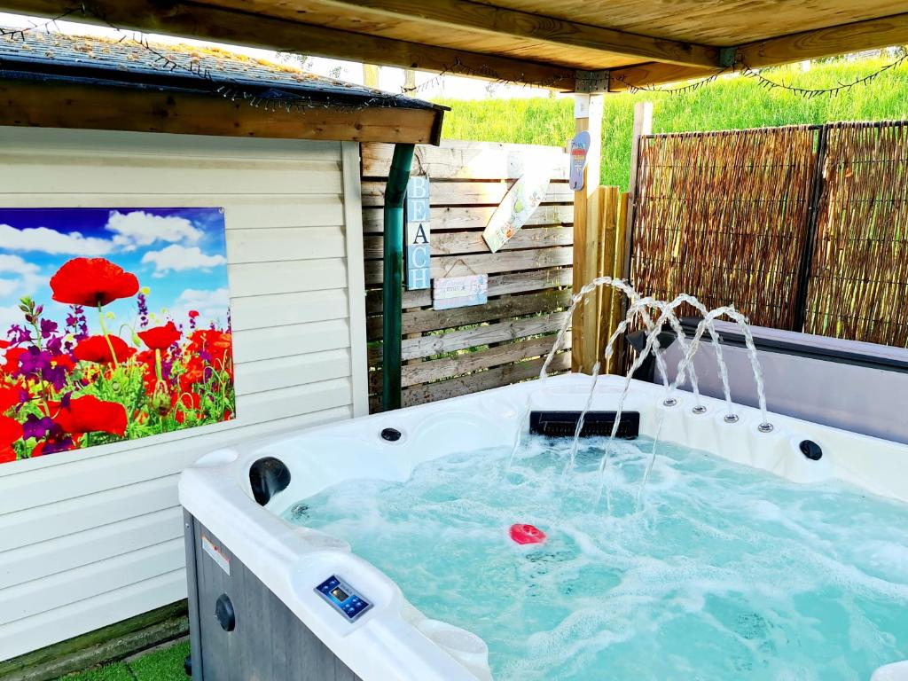 una bañera de hidromasaje en un patio trasero con una pintura de flores en De Corner van Zeeland met jacuzzi en Sint Annaland