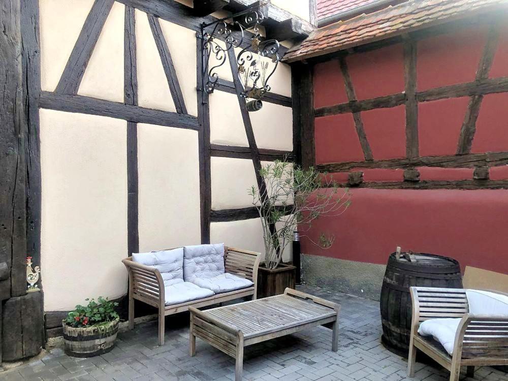 a patio with two chairs and a bench and a barrel at Gîte de l&#39;ours grognon in Dambach-la-Ville