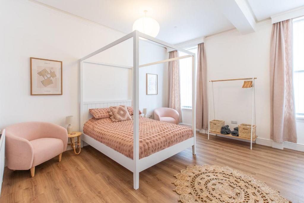a bedroom with a canopy bed and a chair at Banc Apartment 1 in Porthmadog