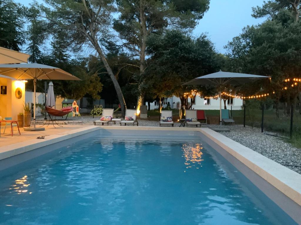 una piscina con sombrillas y un patio en Gîte dans les pins avec piscine, en Mazan