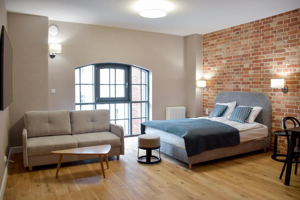 sypialnia z łóżkiem i kanapą w obiekcie Apartamenty Nowy Browar Gdański w Gdańsku
