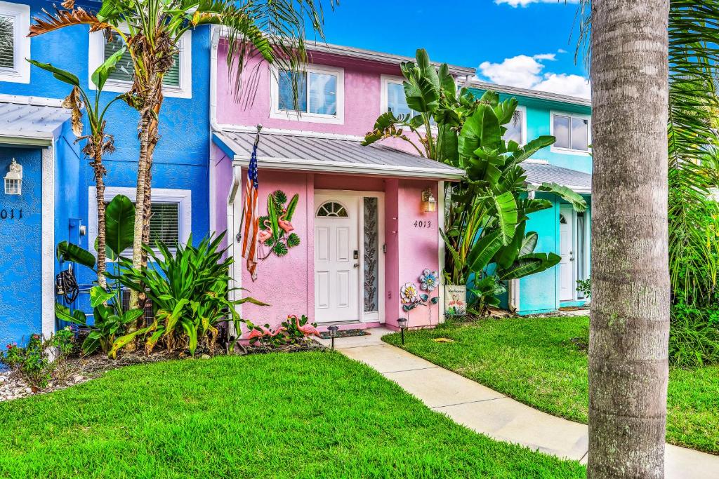 una fila de casas coloridas con palmeras en Flamingo Cottage en New Smyrna Beach