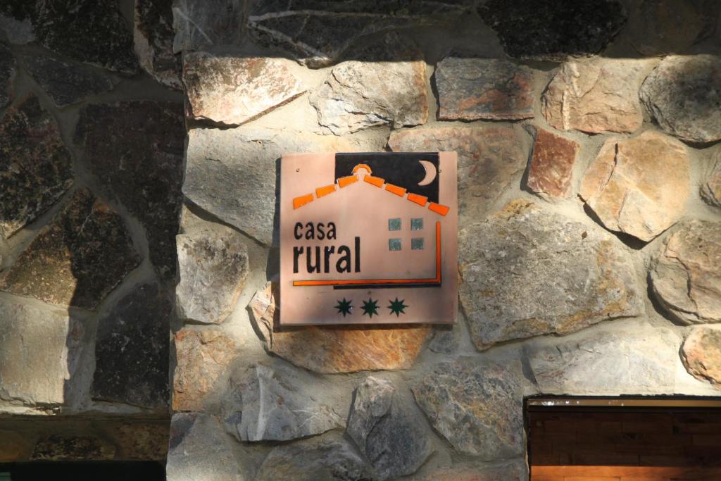 een bord op een stenen muur met een huis erop bij El Descanso de Sanabria in Trefacio