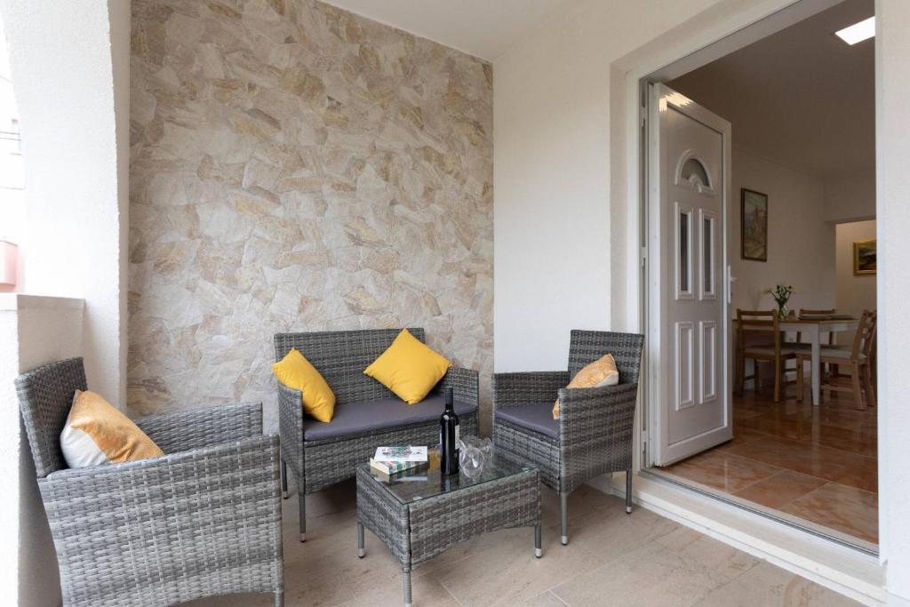 - un salon avec des chaises en osier et un mur en pierre dans l'établissement Apartment Maestral, à Mlini