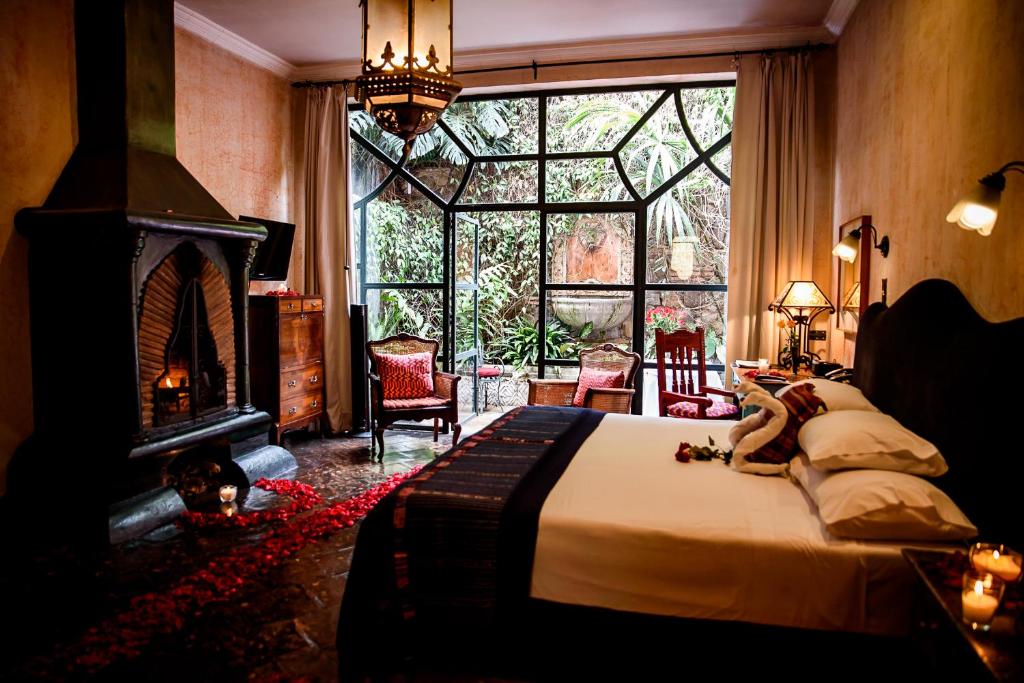 a bedroom with a bed with a fireplace and a large window at Meson Panza Verde in Antigua Guatemala