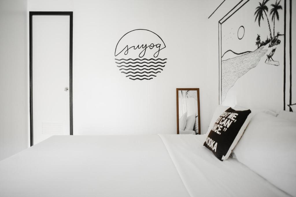a bedroom with two beds and a surfboard on the wall at Suyog Life Siargao in General Luna