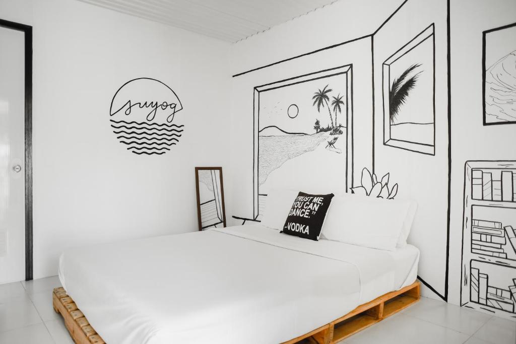 1 dormitorio con 1 cama con un dibujo en la pared en Suyog Life Siargao, en General Luna