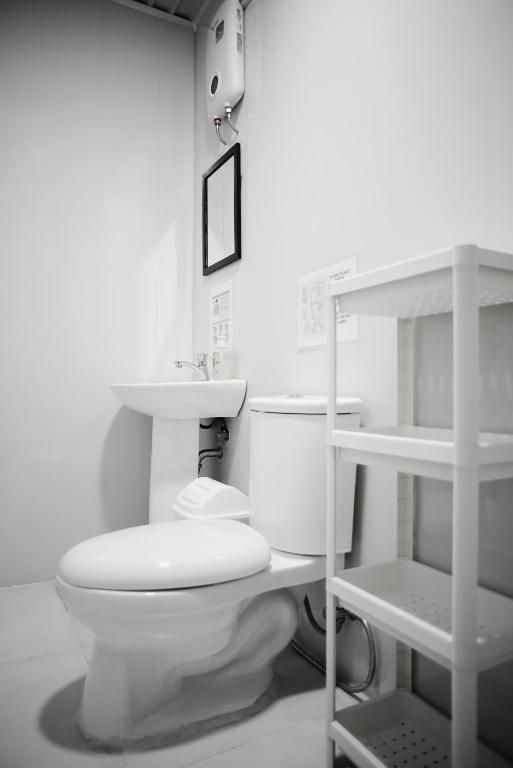 a white bathroom with a toilet and a shelf at Suyog Life Siargao in General Luna