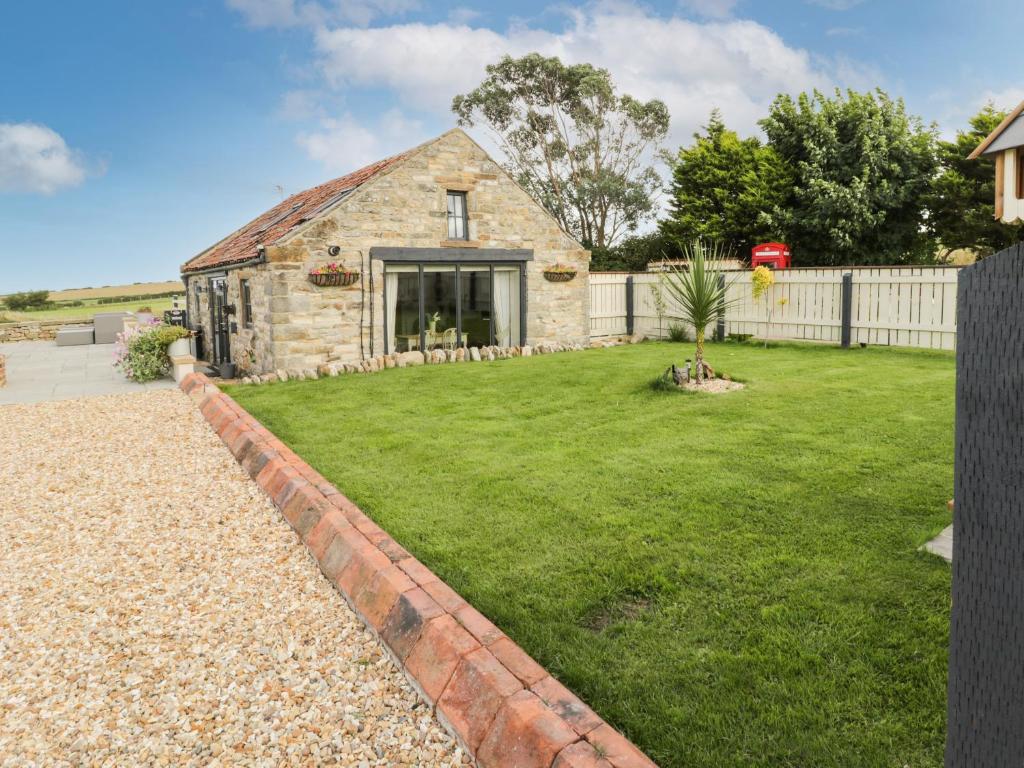 a stone house with a garden and a fence at The Cowshed in Whitby