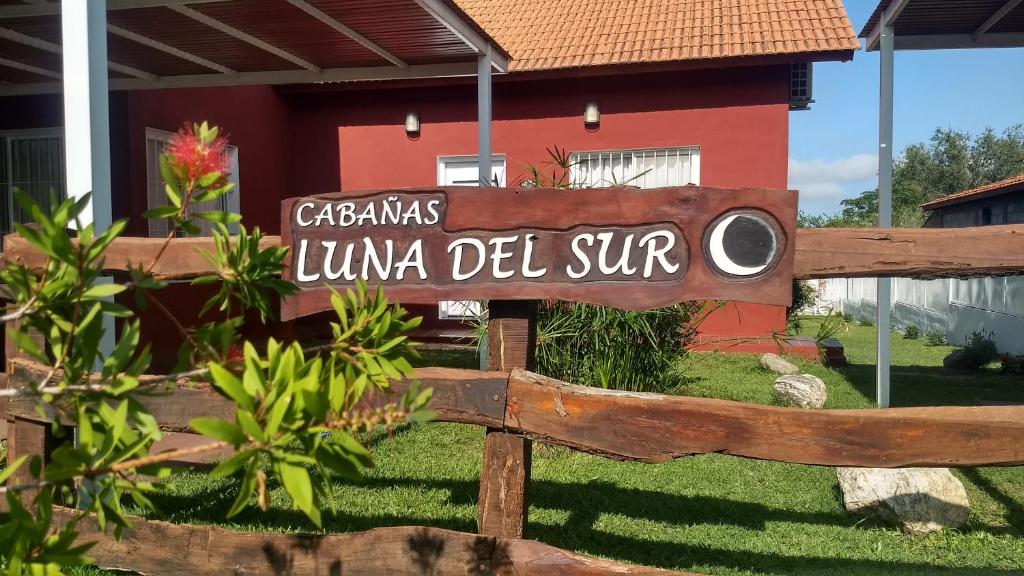 un cartel en una valla de madera frente a una casa en Cabañas Luna del Sur en Merlo