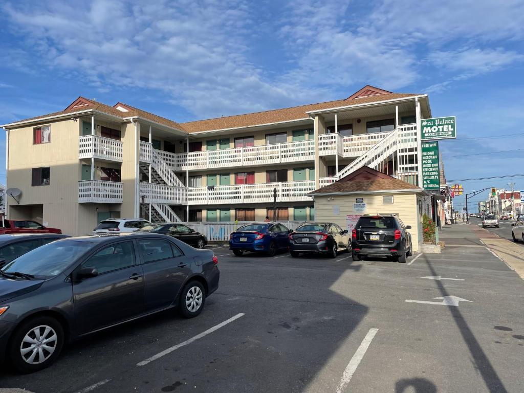 a parking lot with cars parked in front of a building at Sea Palace Motel in Seaside Heights