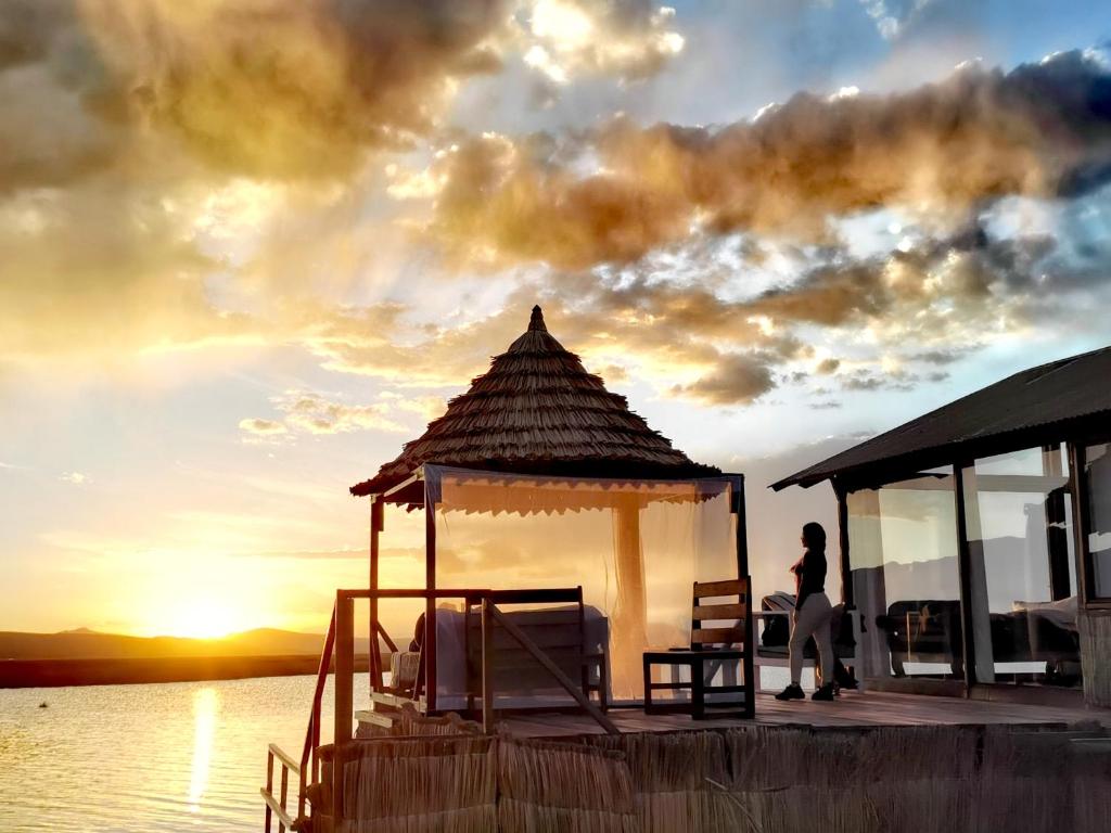 a woman standing on a dock with a gazebo at Titicaca Lodge Peru in Puno