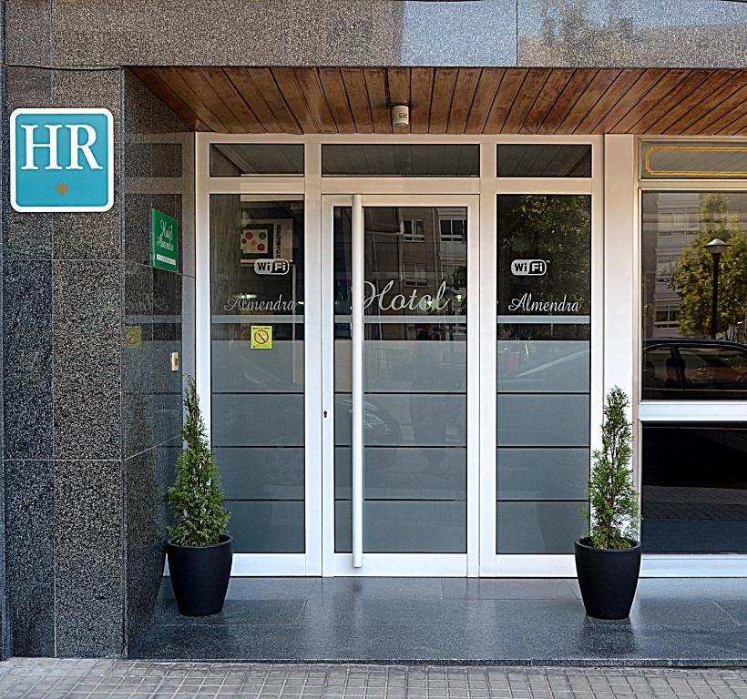 uma frente de loja com dois vasos de plantas em frente em Hotel Almendra em Ferrol