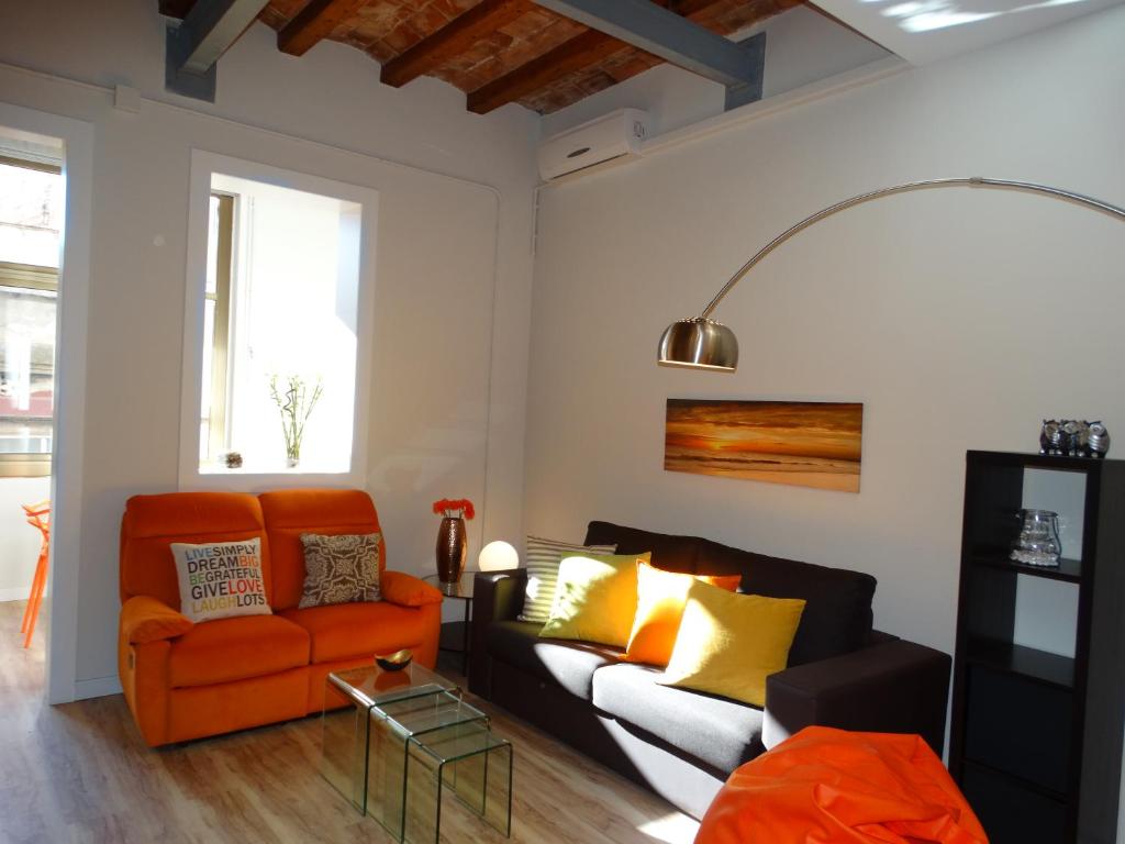 a living room with an orange couch and yellow pillows at Feel at Sants Apartments in Barcelona