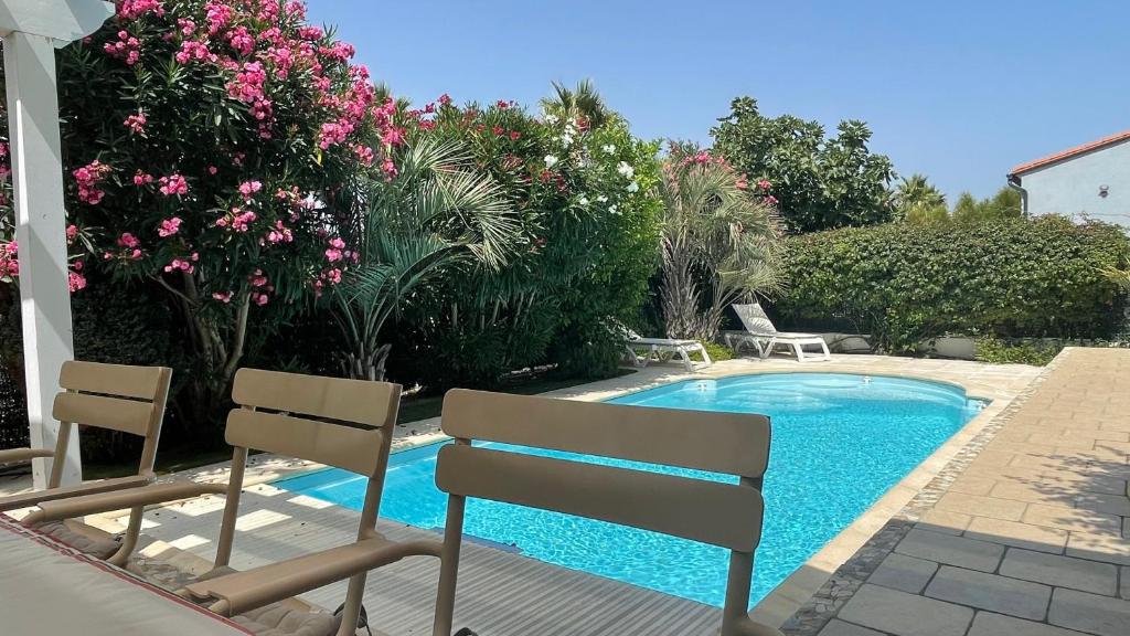 una piscina con 2 sillas y flores en La maison de Virginie en Saint-Cyprien-Plage