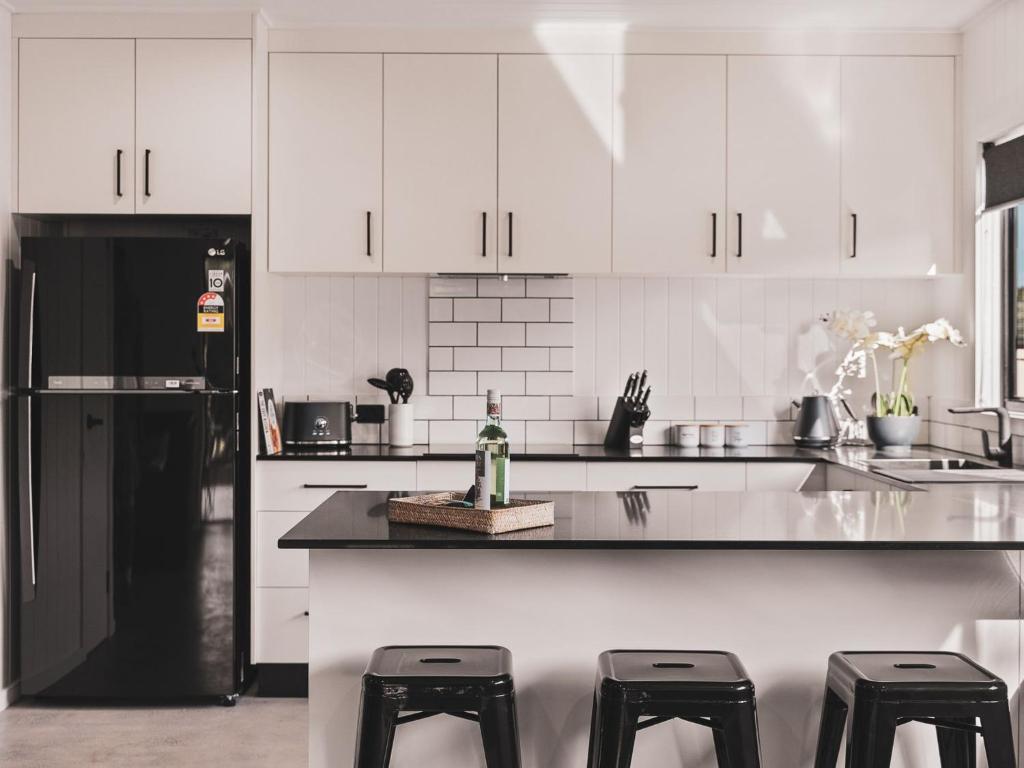 a kitchen with white cabinets and a black refrigerator at Poplar Villa - 1 Poplar Lane in Evans Head