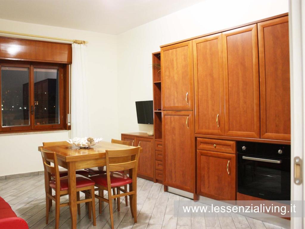 una cucina con armadi in legno, tavolo e sedie di L'ESSENZIAL LIVING a Messina