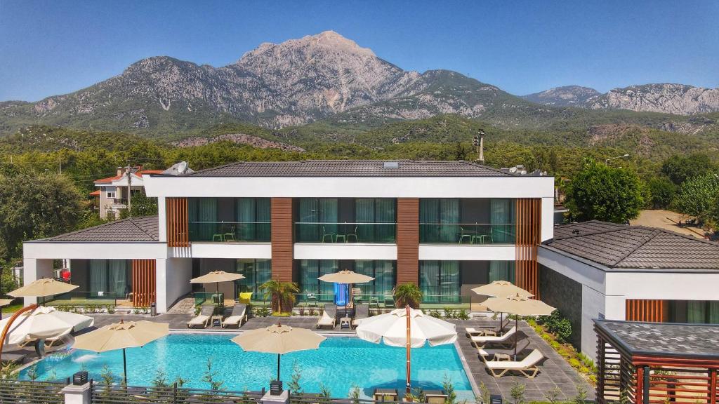 a hotel with a pool and mountains in the background at Güven Park Residance & Hotel in Kemer