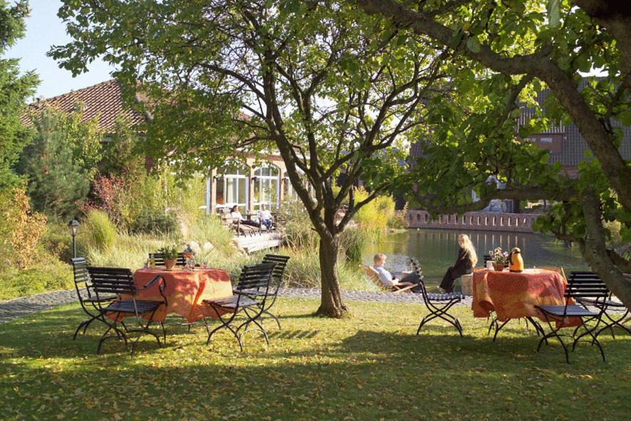 Un groupe de personnes assises à une table dans un parc dans l'établissement EUT-IN Hotel Alte Straßenmeisterei, à Eutin