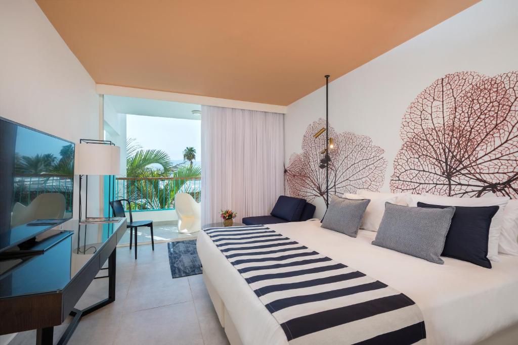 ein Hotelzimmer mit einem großen Bett und einem Schreibtisch in der Unterkunft Yam Suf by Isrotel Collection in Eilat